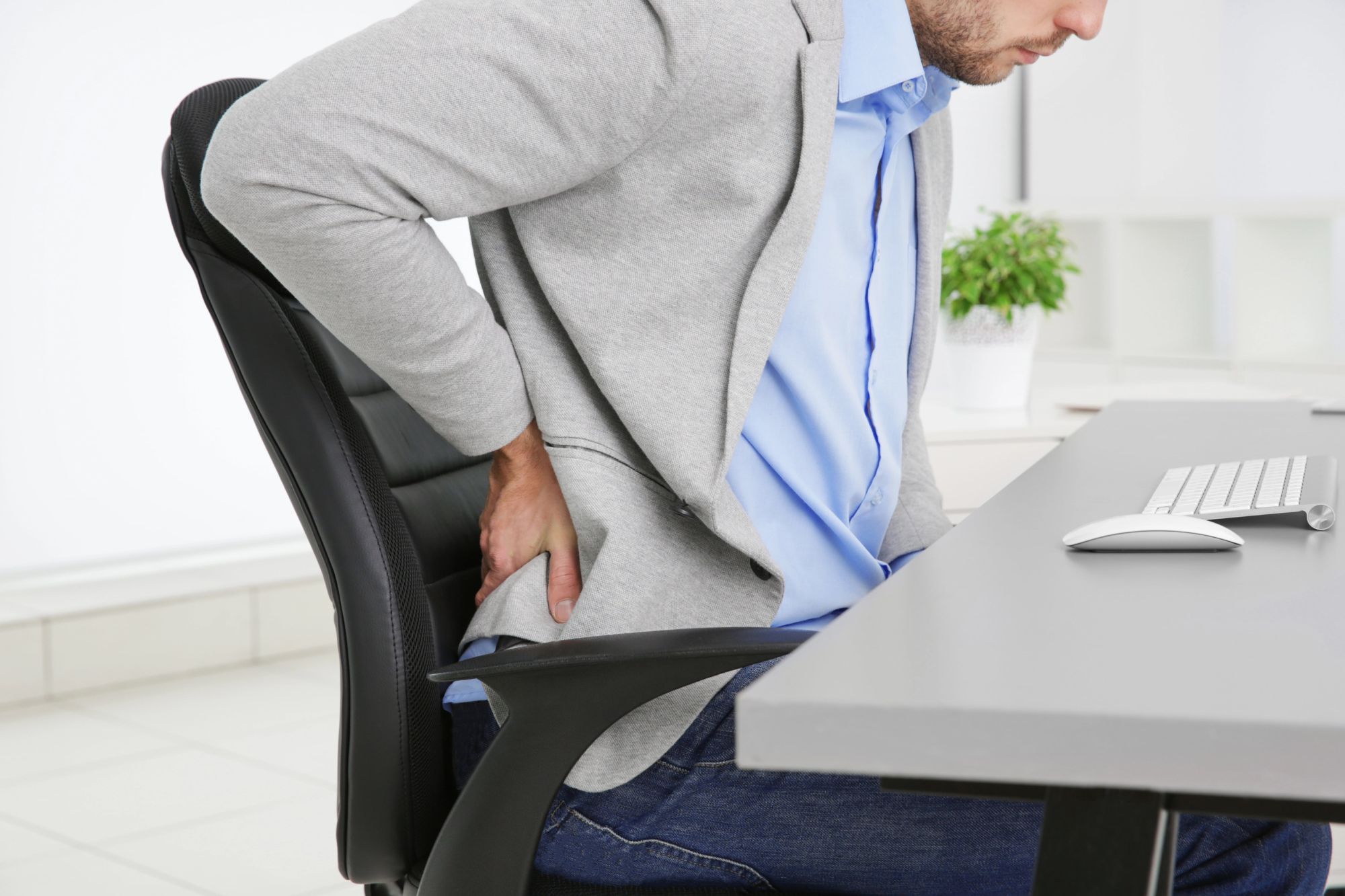 Man in office experiencing severe lower back pain after injury aggravation